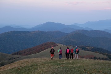 Hiking group of tourist around peak Lomis Mta in Borjomi-Kharagauli National Park, Georgia. Amazing autumn colours in evening sunlight.