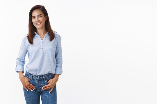 Casual good-looking adult 30s mother keep conversation child teacher, stand relaxed friendly smiling, hold hands loose jeans pockets, look camera amused, standing white background upbeat - Powered by Adobe