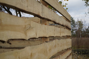 Wooden fence on a background of green trees. A fence of wood against the backdrop of an autumn forest.