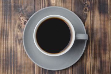 Grey cup with black coffee on on dark wooden table. Top view. Coffee break.