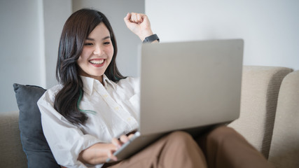Casual young woman using laptop in living room at home