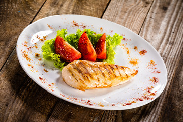 Grilled chicken fillet and vegetables on white plate