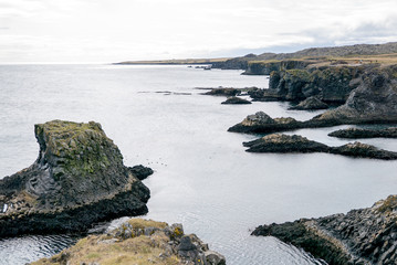 The Cliffs of Arnastapi auf Island mit einer auffallend erodierten schwarzen Steilk&uuml;ste mit H&ouml;hlen, Felstoren und Resten von Kratern