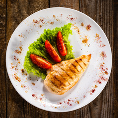 Grilled chicken fillet and vegetables on white plate