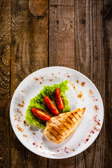 Grilled chicken fillet and vegetables on white plate