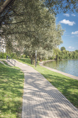 Walkway in the park along the river. Beautiful landscape of summer.