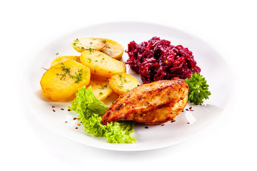 Grilled chicken breast, baked potatoes and vegetables on white background