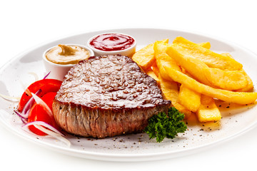 Grilled steaks, French fries and vegetables