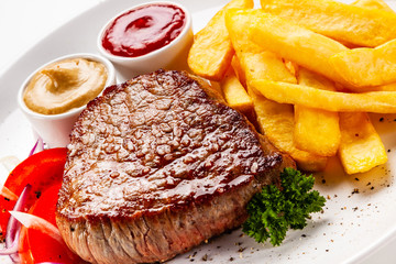 Grilled steaks, French fries and vegetables