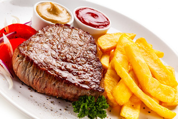 Grilled steaks, French fries and vegetables