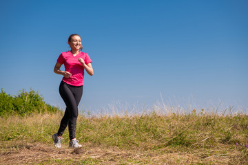 young woman jogging on sunny day at summer mountain