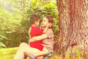 mom and son have fun under a tree in the summer. toned