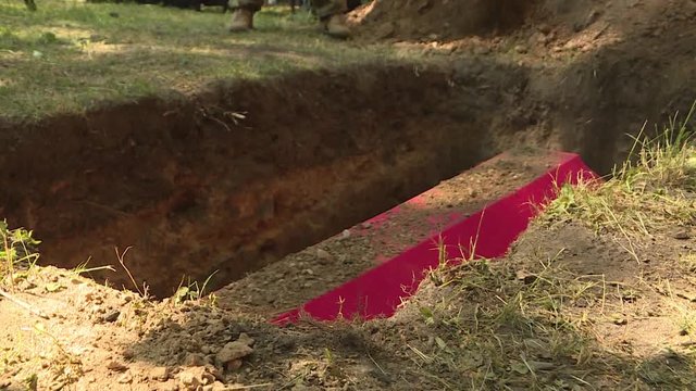 Red coffin in the grave. Military grave-burial of military personnel or civilians who died during hostilities.