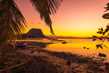 Fishing boats in a quiet ocean at sunset time. Le Morn mountain at Mauritius.