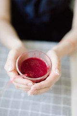 Young woman is holding useful smoothies red from fresh berries and fruits in cafe