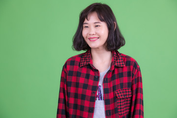 Portrait of happy beautiful Asian hipster woman thinking