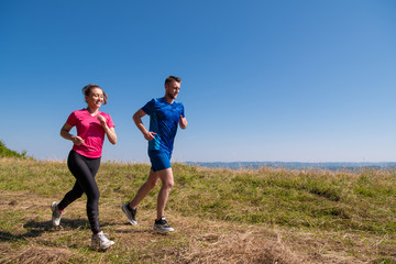 young couple jogging on sunny day at summer mountain