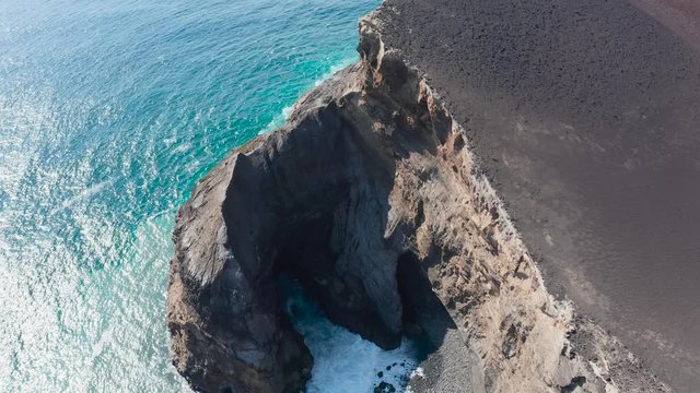 Deep grotto in a rocky cliff and lifeless plateau ща Capelinhos volcano. Aerial of Faial, Azores