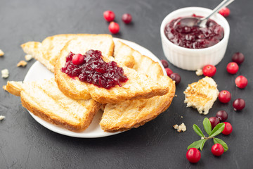 Cranberries jam. Crispy sandwich with cranberry sauce on dark background. Top view.