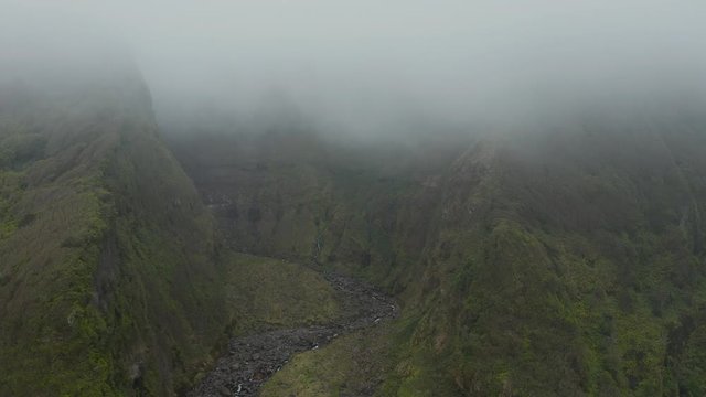 Stony riverbed in ravine. Green mountain coveres with cloud. Aerial of Ferreiro river, Flores, Azores