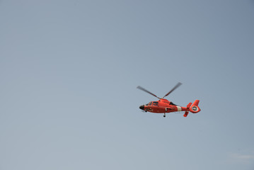 Fototapeta na wymiar Orange helicopter flying in a cloudless sky