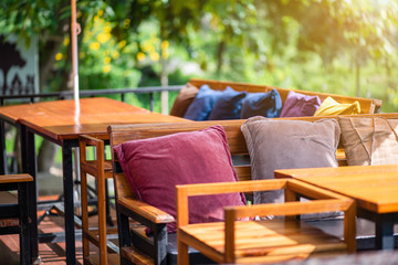 The decoration of the living room by using wooden furniture and colored cushions in the midst of nature.
