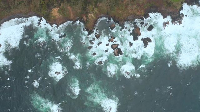 Top view of ocean coastline. Waves crush on rocks and stony beach. Aerial shot