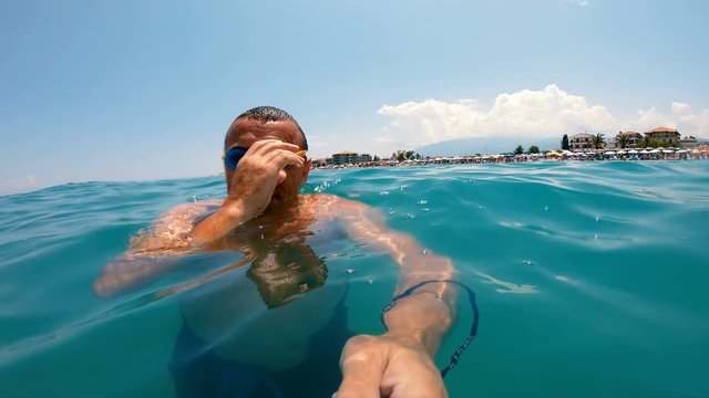 Swimmer putting his goggles on and diving in the crystal clear water