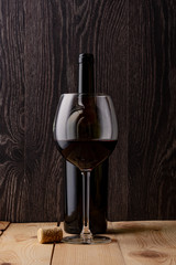 Wine bottle and a glass of wine. Wood background. Natural cork.