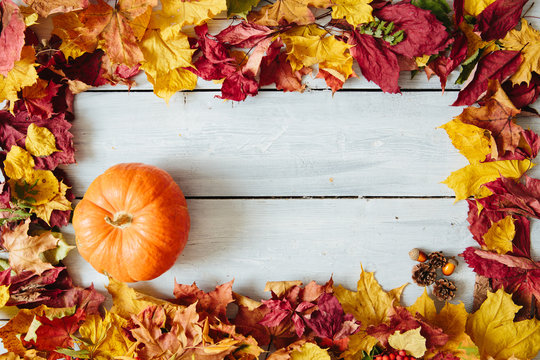 Frame from autumn leaves with pumplin on wooden background. Thanksgiving and Halloween concept. View from above. Top view. Copy space for text and design