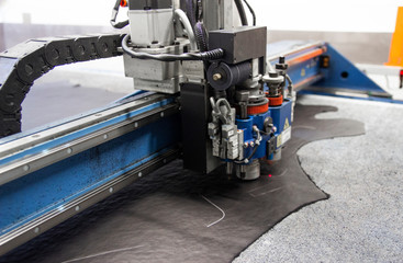 CNC machine for cutting fabrics textile materials and leather. Modern footwear production. Industrial multi-layer leather and fabric cutting machine.