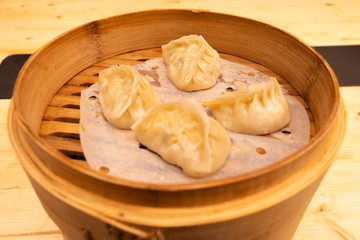 White meat, shrimps and mushroom steamed dumplings on a wooden table in a wooden steamer in an asian restaurant or chinese bar with dumplings.