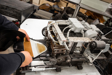 Man use special machine tool for making a shoes. The conveyor on a shoes factory with shoe and sole. Mass production of footwear.