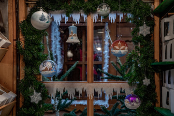 Christmas tree with toys. Hanging Christmas ornaments on blurred background of window framed by artificial conifer branches and tinsel. Traditional Christmas ornaments in shapes of glass balls 