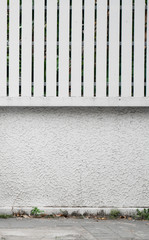 White concrete wall with a wood fence on a street.