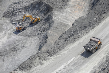 Excavator loads ore into a large mining dump truck. Open pit. Top view © shubas