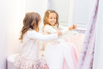 shopping. discounts. little girl shopaholic. girl trying on a beautiful dress gently pink in the fitting room of the boutique. shopping center, shopping. emotions