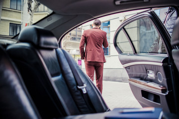 Businessman talk on mobile next to his sedan