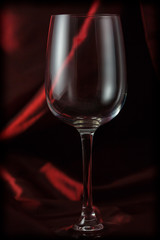 Empty wine glass on a satin red background.
