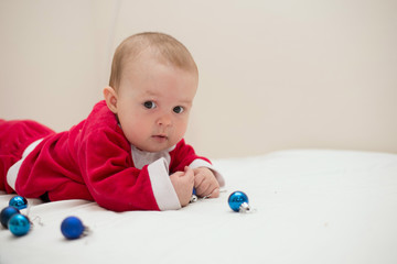 Sweet baby wearing Santa costume with blue balls, over white background with copy space