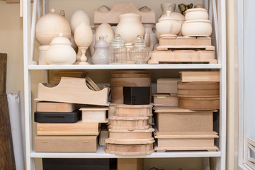 Unfinished wood parts on a shelf for art crafting needs. Craft Supplies. Boxes, eggs, vases.
