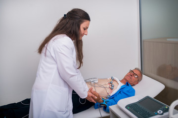 Doctor ( cardiologist ) is attaching vacuum sensors to an elder ( senior )patient for recording ECG...