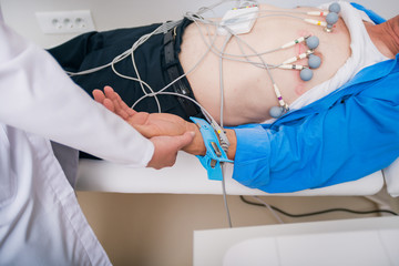 Doctor ( cardiologist ) is attaching vacuum sensors to an elder ( senior )patient for recording ECG...