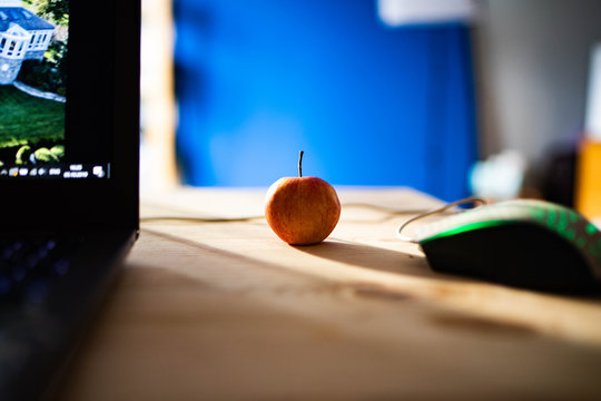 Small red apple on a wooden table with a laptop and a computer mouse - Powered by Adobe