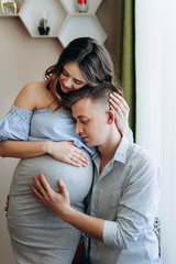 Romantic portrait of beautiful pregnant woman with her handsome husband standing together and hugging