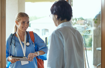 A young doctor is standing at the entrance to the house of a yo