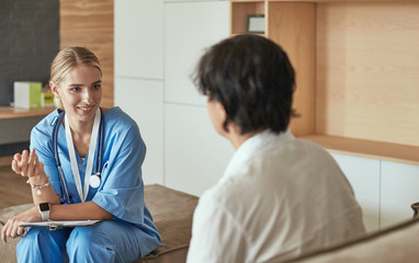 Fototapeta premium Friendly smiling doctor and patient sitting on the couch. Very