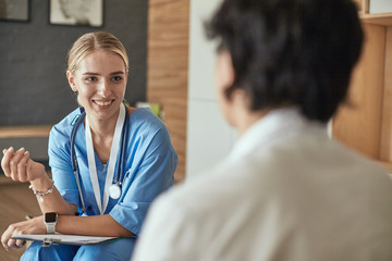 Friendly smiling doctor and patient sitting on the couch. Very