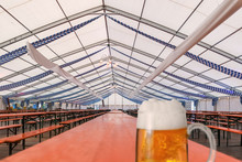 Fertiges und noch leeres Festzelt für das Oktoberfest mit, auf einem Holztisch steht ein Glas Bier