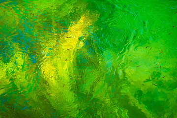 Green, blue and yellow reflections in the river. Abstract colorful background